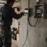 Électricien en train de fixer une wallbox sur un mur de garage