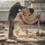 Sac de béton tout prêt de 35 kg ouvert à côté d'une bétonnière